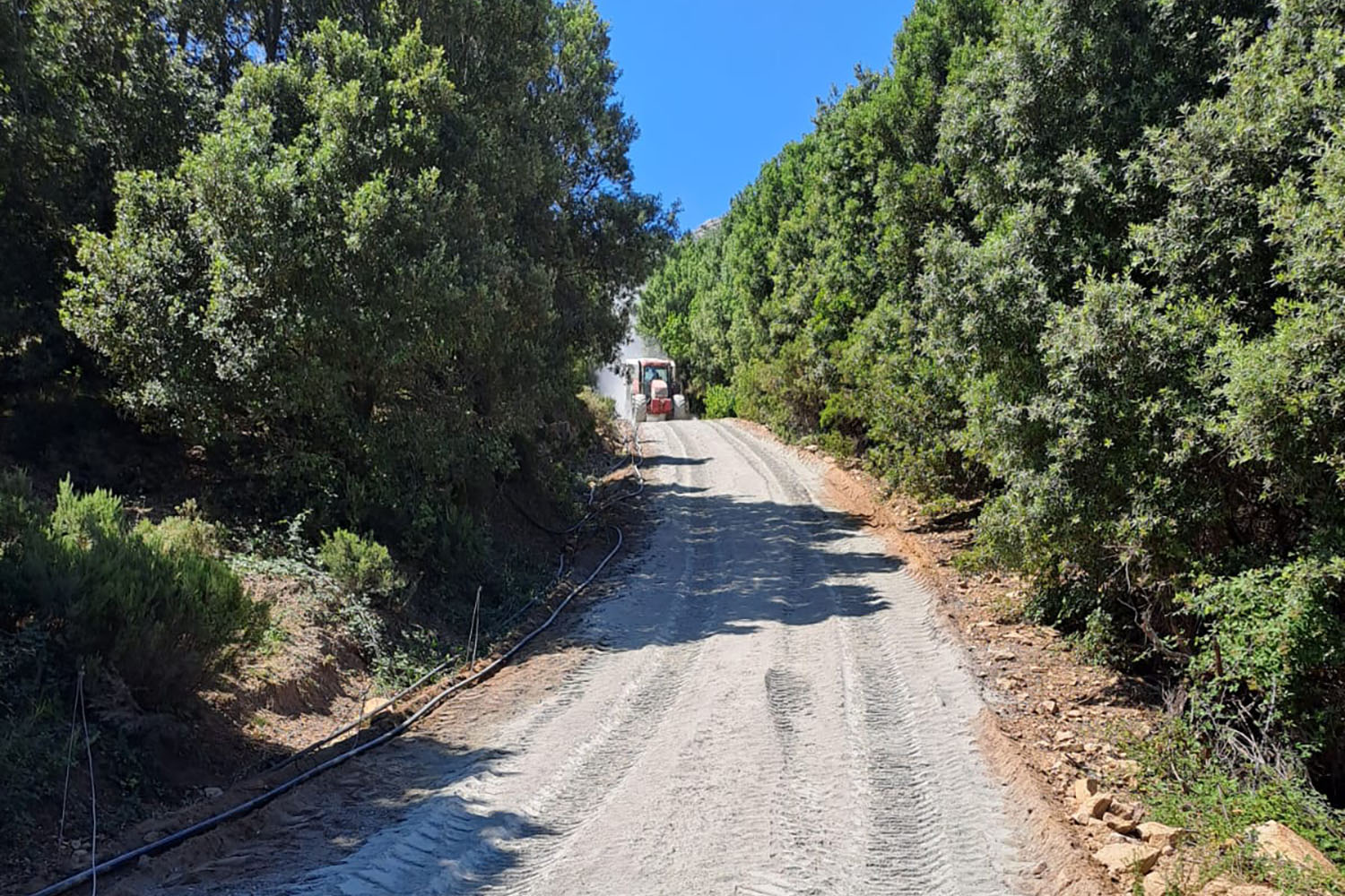 Macchinario operatore al lavoro per la sistemazione della strada rurale Li Conchi a Calangianus. Dettaglio del fondo granitico riprofilato e compattato per gestire le pendenze del Monte Limbara.
