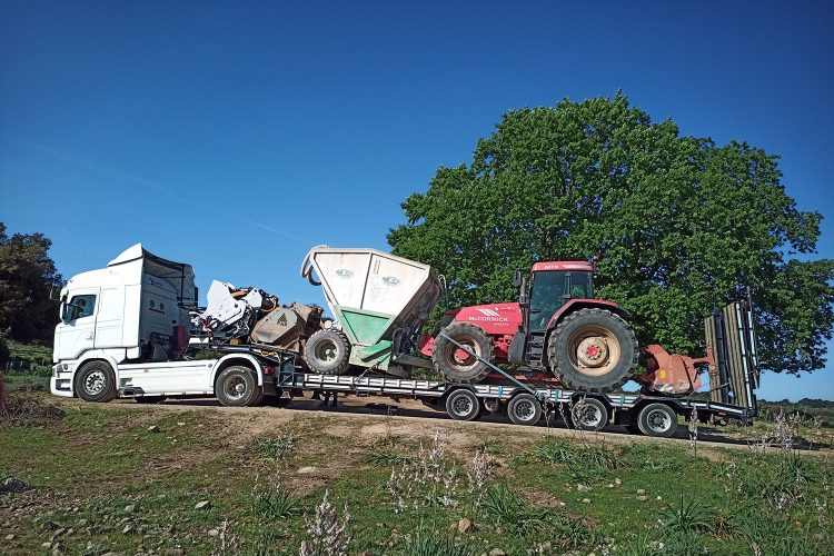 Autoarticolato che trasporta macchine operatrici specifiche come stabilizzatrice e spandi-legante su una strada sterrata in Sardegna
